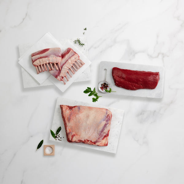 Raw meat cuts on white plates with a light background
