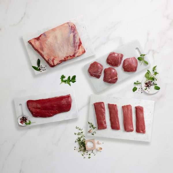 Raw meat cuts on white marble surface with herbs and spices