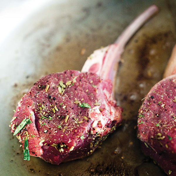 Raw lamb chops with herbs on a pan