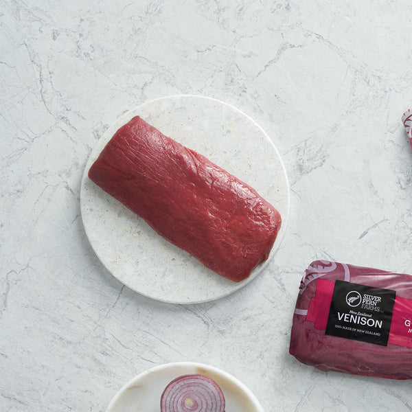 a piece of venison boneless short loin on a white plate with a packaging label on a light gray surface