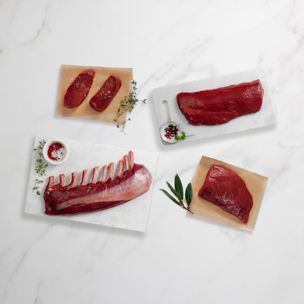 Various cuts of raw meat on white and wooden boards with a light background