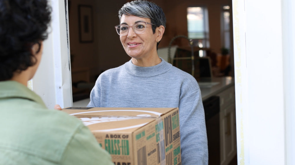 Woman receiving a package from a delivery person at her door.