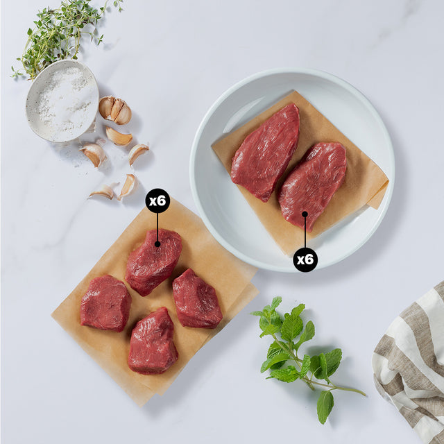 4 Pieces of lamb medallions with x6 blurb and 2 pieces of lamb steaks with x6 blurb placed with garlic cloves, herbs, and salt at the side