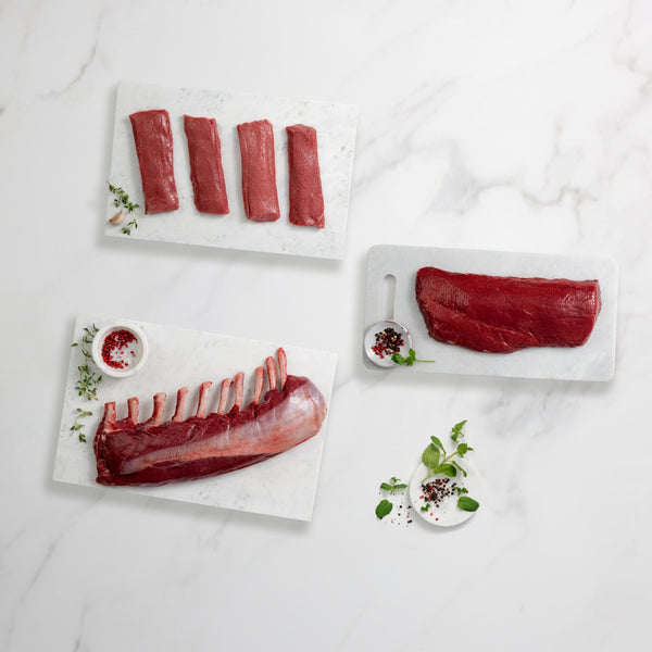 Raw meat cuts on white marble with garnishes