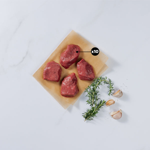 4 Pieces of Silver Fern Farms Lamb Medallion showing x10 blurb placed on paper with rosemary, garlic cloves, and a bit of salt l at the side