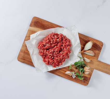 Silver Fern Farms Premium Ground Beef placed on board with garlic cloves and herbs