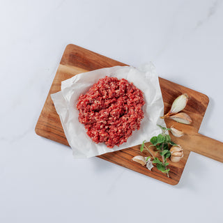 Silver Fern Farms Premium Ground Beef placed on board with garlic cloves and herbs