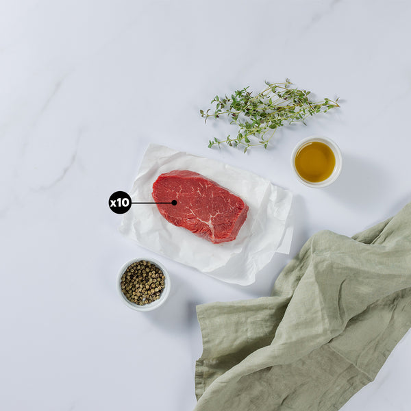 8oz Top Sirloin Beef Steak placed on white paper showing x10 blurb with herbs, pepper and olive oil in bowl, kitchen towel at the side