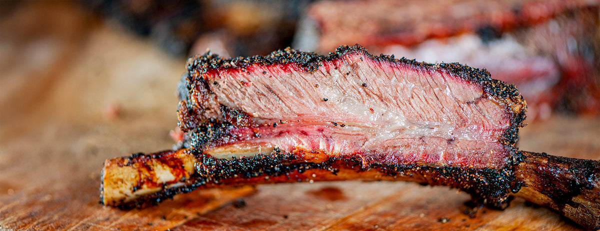 Close-up of a sliced rib with charred exterior on a wooden surface
