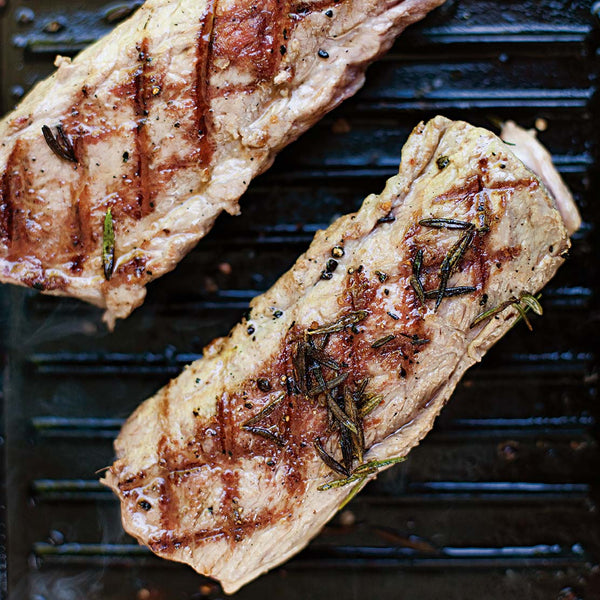 Two pieces of grilled lamb loin meat with grill marks on a griddle