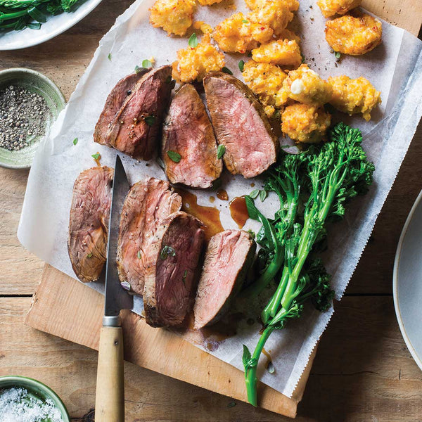 Sliced lamb rumps with vegetables on a wooden cutting board