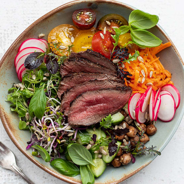 Plated dish with sliced venison, vegetables, and salad